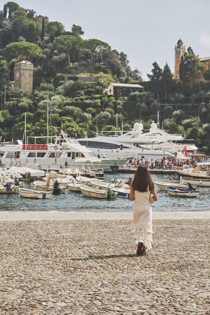 Explore the picturesque harbor of Portofino, Italy, with yachts, boats, and a lush green backdrop in summer.