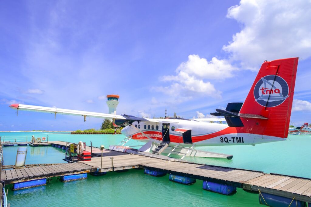 Seaplane at a dock in the Maldives under a vibrant blue sky, offering travel and leisure vibes.