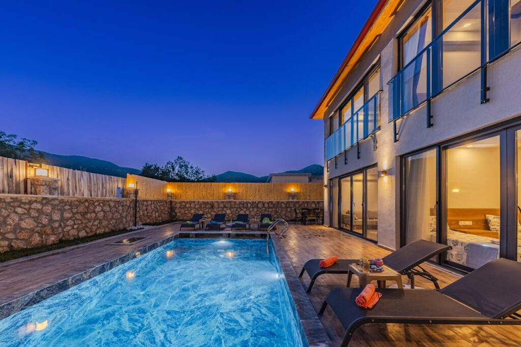 Modern mansion with a swimming pool and sunbeds at twilight, creating a serene evening atmosphere.