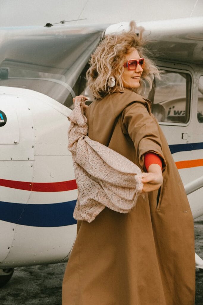 A fashionable woman poses confidently next to a private aircraft with a stylish and modern look.