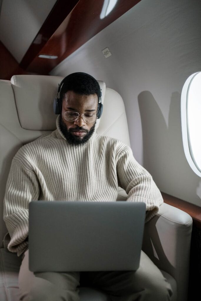 A focused businessman using a laptop and headphones while traveling on a private jet.